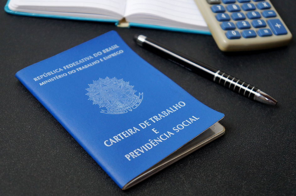 Brazilian work card (carteira de trabalho) on office desk, with calculator, notepad and pen. Retirement (aposentadoria) concept.